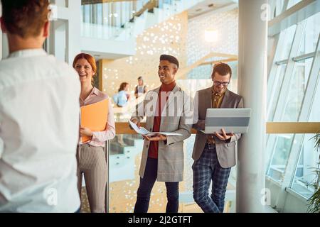 Eine Gruppe junger Geschäftsleute steht im Flur und plaudert in einer angenehmen Atmosphäre. Unternehmen, Mitarbeiter, Unternehmen Stockfoto