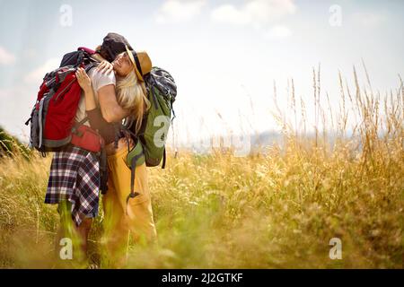 Junges Paar in einer Umarmung, während Sie an einem schönen sonnigen Tag in der Natur spazieren gehen. Wandern, Beziehung, Natur, Aktivität Stockfoto
