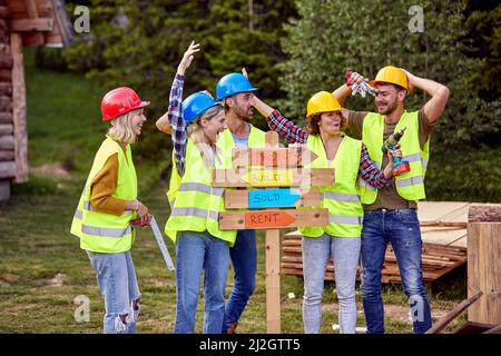 Teamarbeit lächelnde Holzarbeiter mit Holzbrett.Holzhaus Struktur, Bau und Gestaltung Holzrahmen Haus. Stockfoto