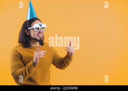 Lächerlich witziger kaukasischer Mann mittleren Alters, der einen riesigen Geburtstagsbecher und eine ungewöhnliche Brille mit Regenbogen trägt. Studioaufnahme. Geburtstagsfeier Konzept. Hochwertige Fotos Stockfoto