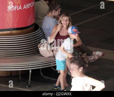 SOFIA, BULGARIEN - 31. JULI 2017: Reife Frau lächelt auf Mobiltelefon, das in einer U-Bahn-Station zum Flughafen Sofia sitzt Stockfoto