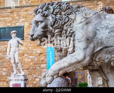Einer der Medici-Löwen mit einer Kopie der Davidstatue Michelangelos im Hintergrund, Florenz, Toskana, Italien Stockfoto