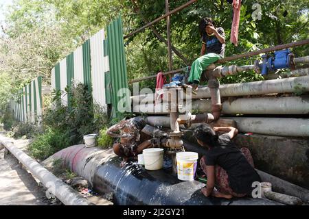 Neu-Delhi, Indien. 01. April 2022. Eine Familie wäscht und badet am 1. April 2022 bei heißem Wetter in Neu-Delhi, Indien, in Leckwasser aus einer Pipeline. (Foto: Ravi Batra/Sipa USA) Quelle: SIPA USA/Alamy Live News Stockfoto