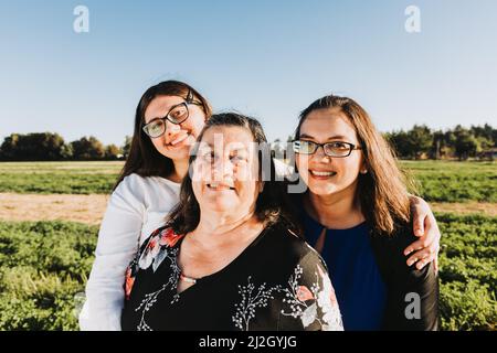 Weibliche Familie lächelt und umarmt auf dem Feld an einem sonnigen Tag Nachmittag. Muttertag. Stockfoto