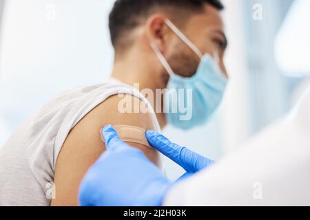 Du bist ganz eingestellt. Aufnahme eines nicht erkennbaren Arztes, der ihrem Patienten ein Pfandhilfsmittel auflegte, nachdem er ihm den Covid-Impfstoff gegeben hatte. Stockfoto