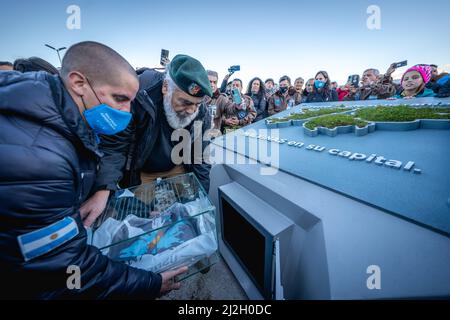 Ushuaia, Argentinien. 01. April 2022. Eduardo Cequeira (r), argentinischer Fregatte-Kapitän, und sein Sohn (l) legen während einer Gedenkfeier zum 40.. Jahrestag des Starts des Falklandkrieges eine Glaskapsel mit Dokumenten aus dem Falklandkrieg in eine Kammer. Die Neueröffnung der Kapsel ist für 2082 geplant. Am 2. April 1982 griffen argentinische Truppen die Falklandinseln an, die seit 1833 von Großbritannien regiert werden. Im Jahr 2022 erneuerte der argentinische Präsident Fernandez den Anspruch des südamerikanischen Landes auf das britische Überseegebiet. Quelle: Joel Reyero/dpa/Alamy Live News Stockfoto