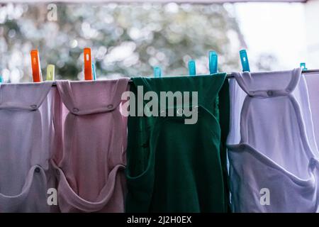 Babybodysuits hängen an einer Wäscheleine und trocknen nach dem Waschen Stockfoto