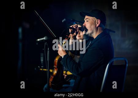 Edinburgh, Schottland. Fr, 1. April 2022. Piper Brìghde Chaimbeul und Fiddler-Spieler Aidan O'Rourke treten im Rahmen des Burns & Beyond Festivals live in der St. Giles' Cathedral auf. Das Konzert fand unter Michael Pendrys Kunstinstallation ‘Les Colombes (The Doves)’ statt, einer geschwungenen Säule aus mehr als 2.500 Origami-Papiertauben, die die gesamte Länge der Kathedrale durchfliegen. Stockfoto