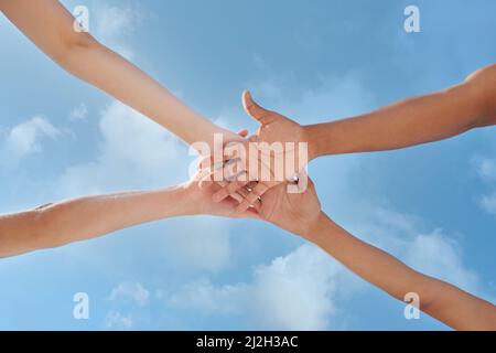Wir können alles erreichen, was wir uns eindenken. Aufnahme einer Gruppe von nicht erkennbaren Personen, die ihre Hände stapeln. Stockfoto