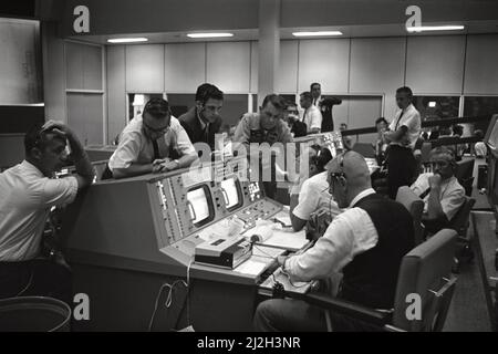 Ansicht der Flight Directors Konsole im Mission Control Center (MCC), Houston, Texas, während des Gemini 5-Flugs. An der Konsole sitzen Eugene F. Kranz (Vordergrund) und Dr. Christopher C. Kraft Jr. (Hintergrund). Vor der Konsole stehen Dr. Charles Berry (links), ein nicht identifizierter Mann im Zentrum und Astronaut Elliot M. See. Stockfoto