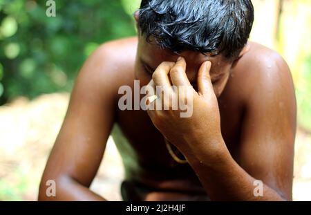 Ein armer asiatischer Mann berührt verzweifelt seine Stirn mit der Hand. Stockfoto