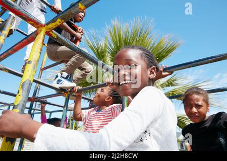 Die Welt ist ihr Spielplatz. Porträt eines glücklichen kleinen Mädchens, das in einem Dschungelgymnastik spielt. Stockfoto