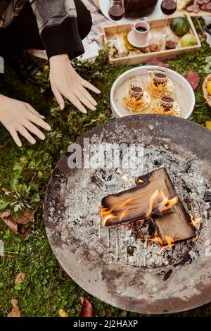 Blick von oben auf die Feuerstelle andÊtea in Gläsern mit Goldhaltern beim Picknick Stockfoto