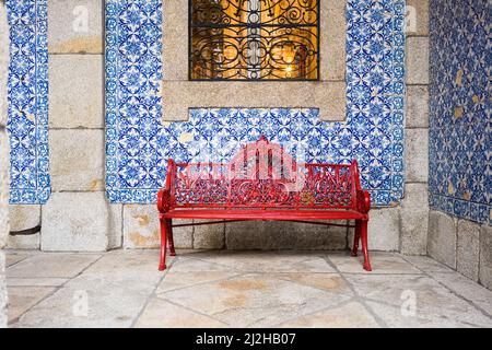 Portugal, Porto, Rote Bank vor der mit Azulejos bedeckten Wand Stockfoto