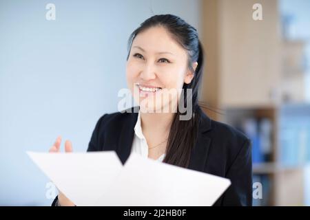 Lächelnde Geschäftsfrau mit Dokumenten im Büro Stockfoto