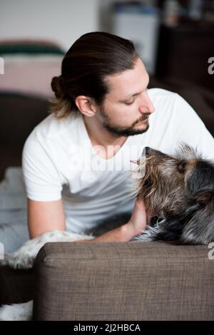 Mann streichelte Dackel auf dem Sofa Stockfoto