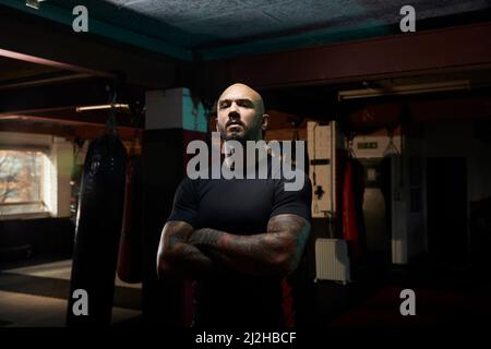 Porträt eines Boxers mit gekreuzten Armen im Fitnessstudio Stockfoto