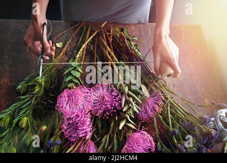 Blumen bringen Farbe in Ihr Leben. Ein kurzer Schuss eines hübschen Blumenstraußes, der auf einer Holztheke abgerundet wird. Stockfoto