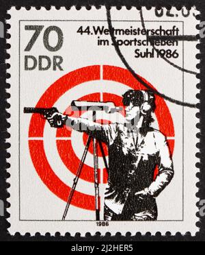 DDR - CIRCA 1986: Ein in der DDR gedruckter Stempel zeigt, wie eine Frau mit Handfeuerwaffe schießt, 44. World Sports Shooting Championships, Suhl, circa 1986 Stockfoto