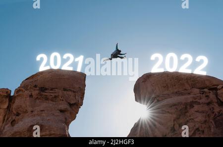 2022 Neujahr Konzept, Silhouette ein Mann springen von Jahr 2021 bis 2022 Stockfoto