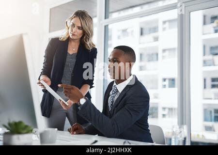 Ein wachsames Auge auf den reibungslosen Ablauf ihrer Pläne. Aufnahme von zwei Geschäftsleuten, die in einem Büro zusammenarbeiten. Stockfoto