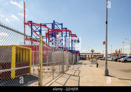 Soarin' Eagle Rollercoaster rot und blau im Luna Park Amusement Park, Coney Island, Brooklyn, Blick von der Seite mit der Stadtstraße und geparkt c Stockfoto