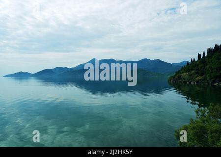 Ruhiger Panoramablick auf die Berge im Skadar See in Montenegro. Ruhige türkisfarbene Landschaft Hintergrund Stockfoto