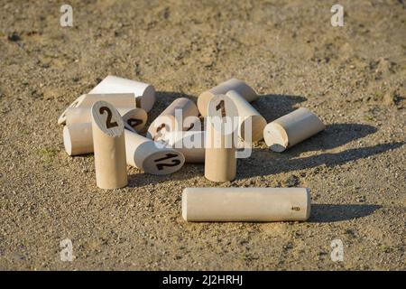 Mölkky Kegeln ausgebreitet auf dem Sandboden einer Bowlingbahn, bis auf zwei, nach dem Werfen des Stabes vor platziert Stockfoto