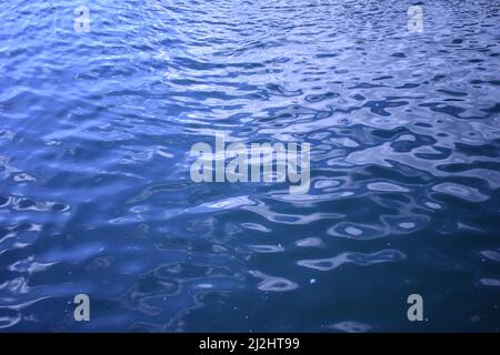 Dunkelblaue wellige Wasseroberfläche. Wasserstruktur des Schwimmbades. Blaue Flüssigkeitsreflexionen. Noch gewelltes Wasser der Küste. Oberflächenstruktur des Swimmingpools. Entfällt Stockfoto