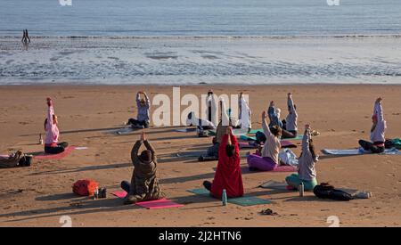 Portobello, Edinburgh Schottland, Großbritannien. April 2022. Erste Beach Yoga Klasse von 2022 am Meer neben dem Firth of Forth. Die Temperatur beträgt etwa 5 Grad Celsius, aber die Sonne gab der harten Gruppe Wärme. Stockfoto