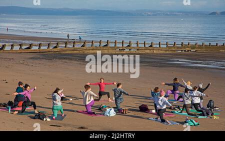 Portobello, Edinburgh Schottland, Großbritannien. April 2022. Erste Beach Yoga Klasse von 2022 am Meer neben dem Firth of Forth. Die Temperatur beträgt etwa 5 Grad Celsius, aber die Sonne gab der harten Gruppe Wärme. Stockfoto