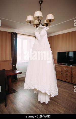 Weißes Hochzeitskleid, das an einem Kronleuchter hängt Stockfoto