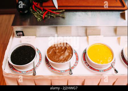 Köstliche süße Saucen in schwarz, rot und gelb, verschiedene Gerichte. Griechische Küche. Stockfoto