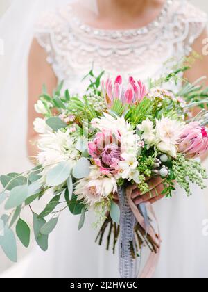 Braut in weißem Kleid hält Hochzeit Blumenstrauß Nahaufnahme Stockfoto