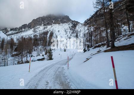 Verschneite Winterstraße in einer Bergwaldlandschaft. Stockfoto