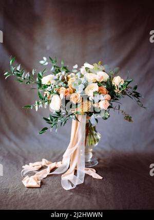 Modernes Bukett in Pfirsich- und Beigetönen auf dunkelgrauem Hintergrund. Blumen-Einladungskarte. Elegante Hochzeitsinspiration. Stockfoto