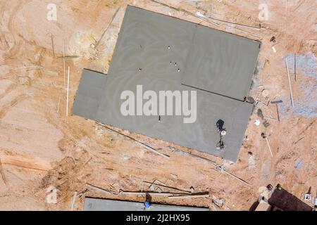 Luftaufnahme des Bauarbeiters mit Maschinenanwendung Schleifzement Estrichfundament auf dem neuen Hauskomplex der Baustelle Stockfoto