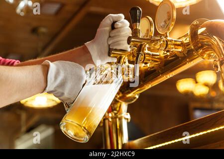 Barkeeper Hände gießen helles Bier in einer Bier Glas Stockfoto