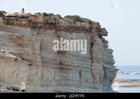 Von der Klippe der Avakas Bay im Akamas Peninsula National Park, Republik Zypern, blickt ein einmunder Radfahrer über das Meer. Stockfoto