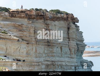 Von der Klippe der Avakas Bay im Akamas Peninsula National Park, Republik Zypern, blickt ein einmunder Radfahrer über das Meer. Stockfoto