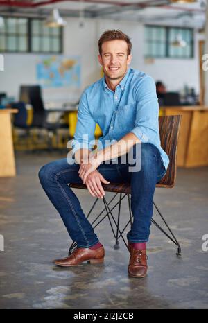 Meine perfekte Karriere gestalten. Porträt eines hübschen jungen Designers, der in einem Büro auf einem Stuhl sitzt. Stockfoto