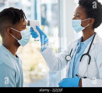 Lassen Sie uns Ihre Temperatur nehmen. Aufnahme einer Ärztin, die die Temperatur ihrer Patientin einnahm. Stockfoto