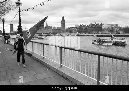 Der Teilnehmer des Kanurennens auf der Themse läuft mit seinem Boot entlang der South Bank, bevor er auf das Wasser geht. 20.. April 1987 Stockfoto