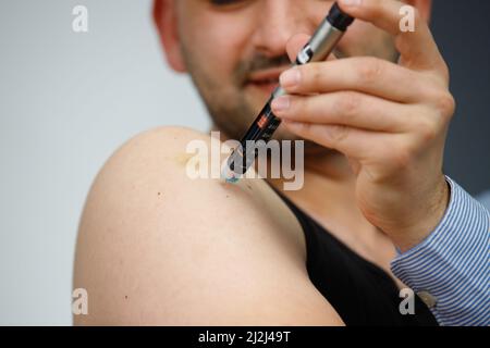 Zugeschnittenes Foto eines Mannes mit einer Spritze, der zu Hause Insulinspritze für sich selbst macht, Diabetes und Gesundheitskonzept. Stockfoto