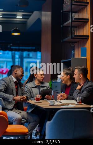 Eine Gruppe von multirassischen Geschäftsleuten lächelt zusammen, während sie redet Stockfoto