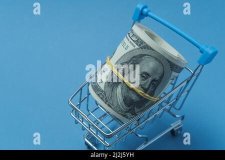 In einen Schlauch gerollte Dollars liegen in einem Einkaufskorb. Stockfoto
