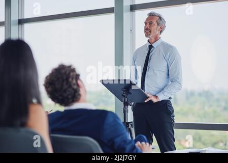 HES spricht aus Erfahrung. Eine Aufnahme eines hübschen, reifen Sprechers, der während eines Seminars auf der Konferenz eine Gruppe von Geschäftsleuten angesprochen hat Stockfoto