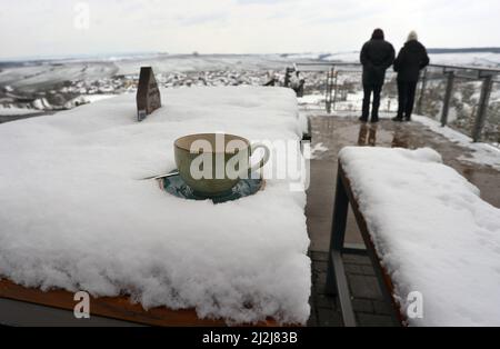 Escherndorf, Deutschland. 02. April 2022. Eine Kaffeetasse steht auf dem verschneiten Tisch eines Ausflugsrestaurants über dem Main Loop. Quelle: Karl-Josef Hildenbrand/dpa/Alamy Live News Stockfoto