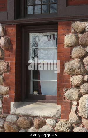 Vintage Holzfenster auf einem charmanten rustikalen Steinhaus. Stockfoto