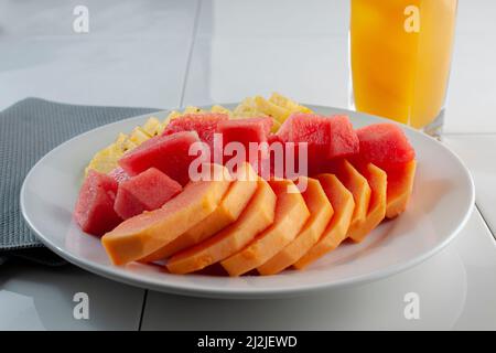 Früchte auf einem weißen Teller, Scheiben Ananas Papaya und Wassermelonenwürfel, Stockfoto